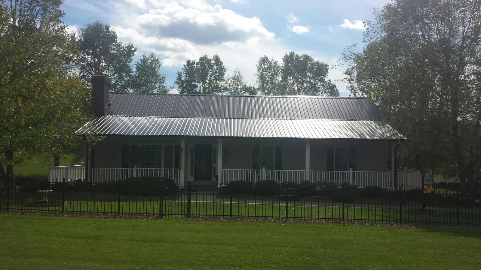 Gray metal roof on a brick ranch with a full width front porch — Gutter Guard Installation work by our crew in Dixon